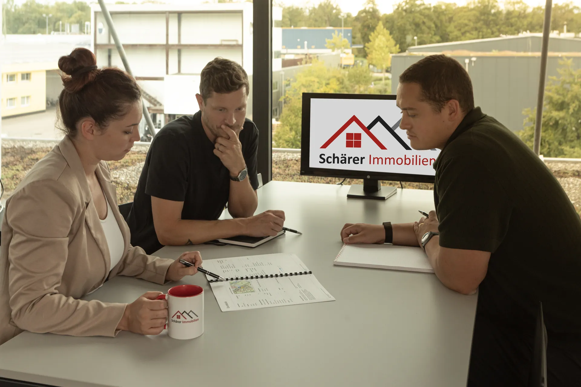 Lara Schärer, Noah Schärer und Lukas Pauli besprechen Unterlagen im Büro der Schärer Immobilien AG in Lyss